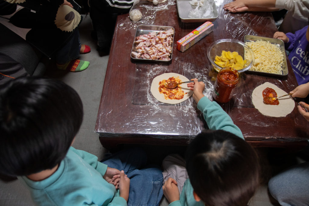 食育応援企画「野菜収穫とピザクッキング」でピザソースを塗る